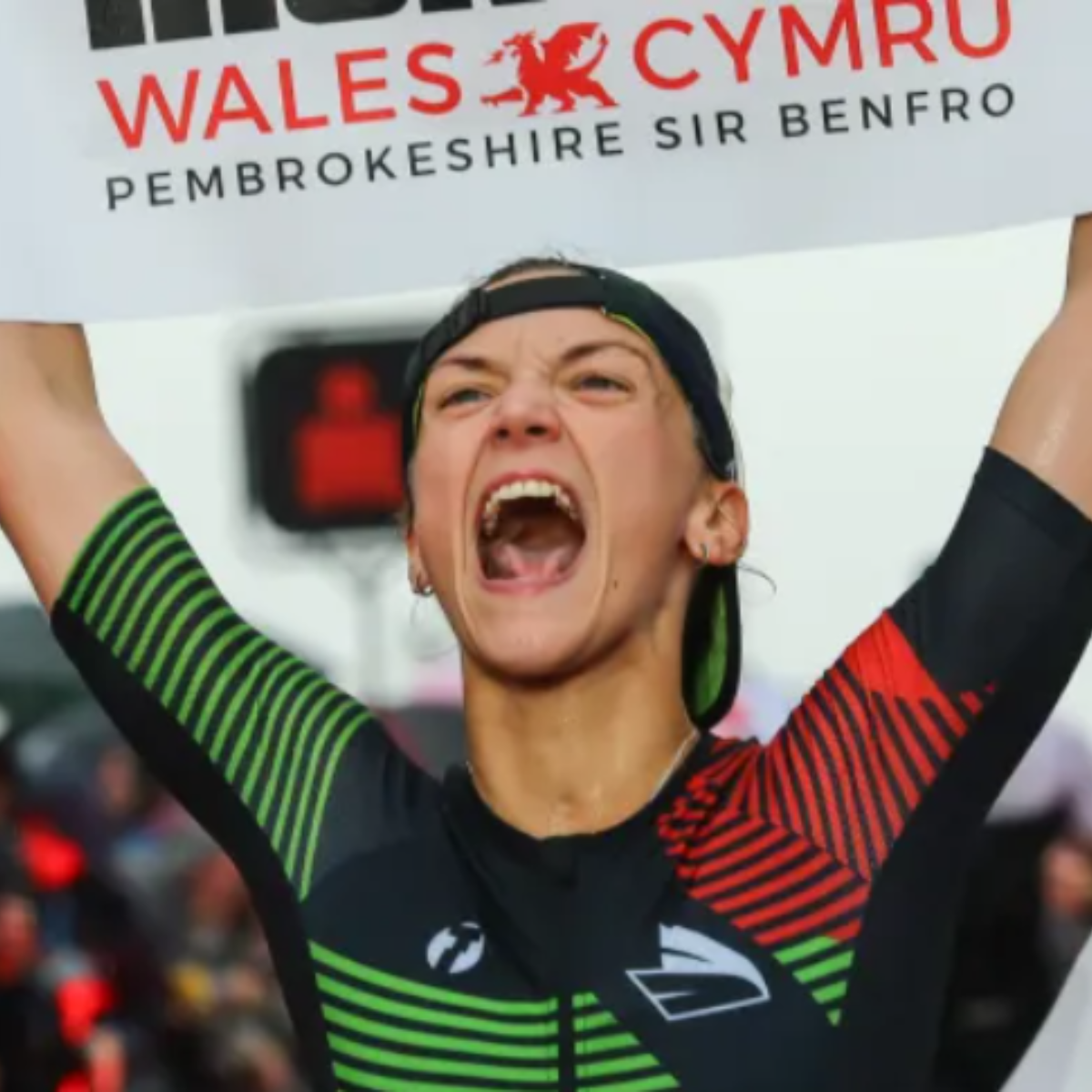 A charity athlete celebrates crossing the finish line of the IRONMAN Swansea 70.3.