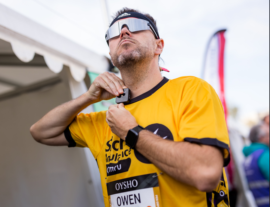 A runner from the Cardiff Half Marathon. He is wearing the St John Ambulance Cymru vest, which fundraisers for St John Ambulance Cymru wear during the race and running goggles.